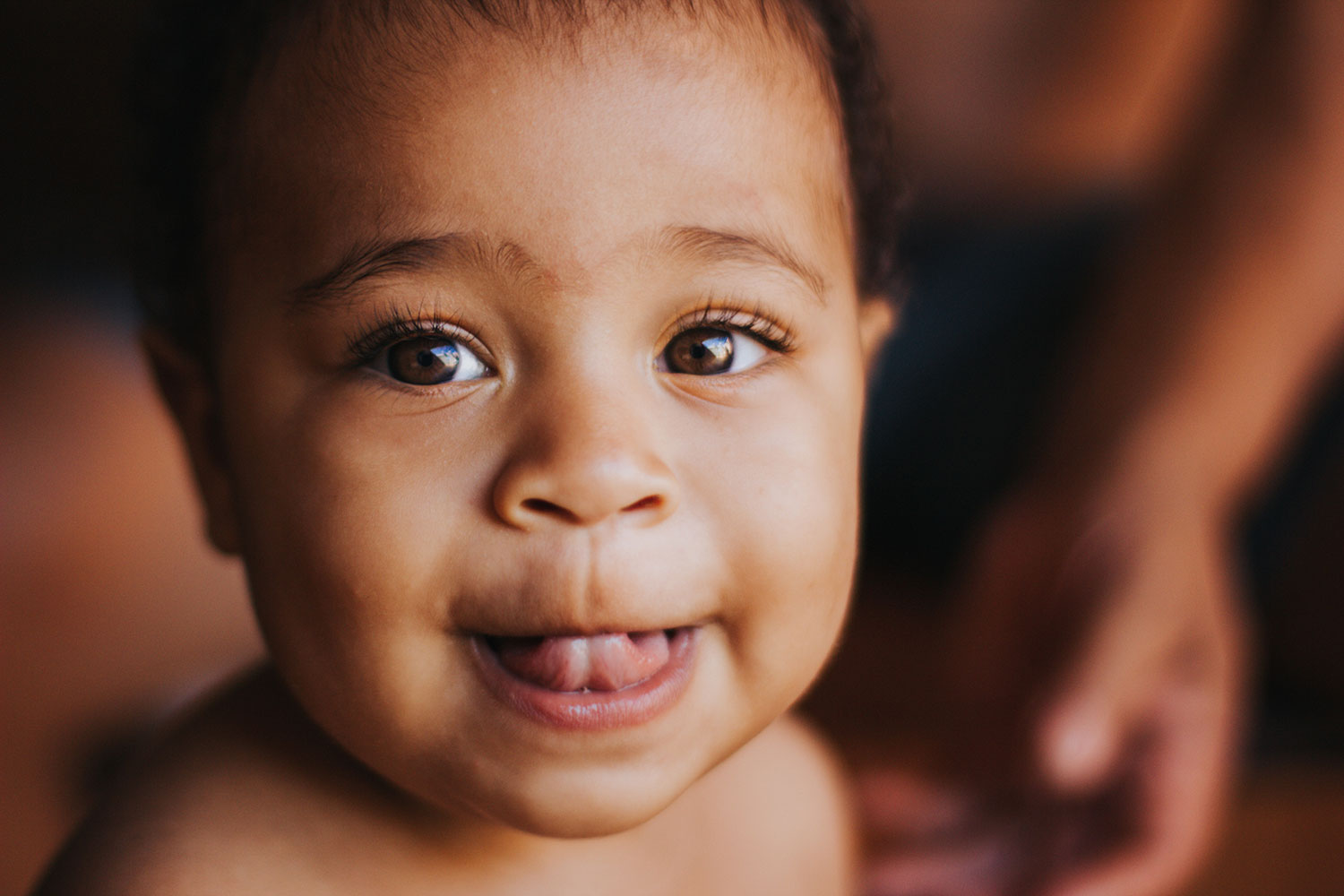 A portrait shot of a cute baby smiling with their tongue out